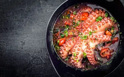 Polpo alla luciana in padella, con pomodorini e prezzemolo. Un piatto succulento e profumato, pronto per essere gustato.