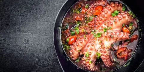 Polpo alla luciana in padella, con pomodorini e prezzemolo. Un piatto succulento e profumato, pronto per essere gustato.