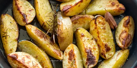 Patate al forno dorate e croccanti, condite con rosmarino e aglio, pronte per essere gustate.