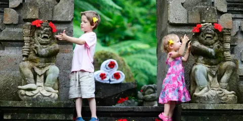 Bambini a Bali esplorano antiche statue decorate con fiori. Un'avventura indimenticabile per i più piccoli.