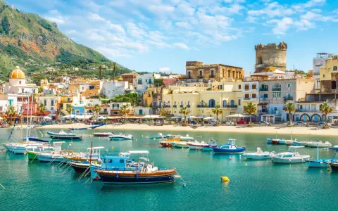 Un incantevole scorcio di Ischia con bambini che sognano gite in barca. Case colorate, mare azzurro e un castello medievale.