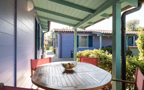 Tavolo con frutta su un portico colorato, con casette in stile villaggi Conero sul mare per bambini sullo sfondo.