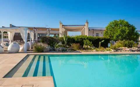Piscina cristallina e lettini bianchi al le cesine resort, sotto un cielo azzurro. Relax e natura.