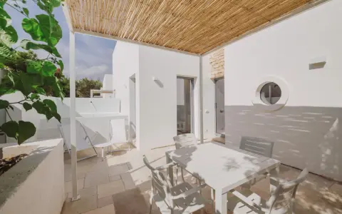 Terrazza con tavolo e sedie bianche, tettoia in bambù, tipica del Nicolaus Club Meditur Village.