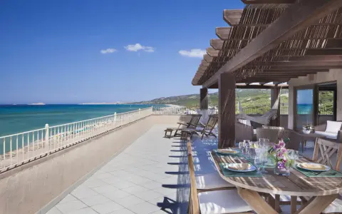 Terrazza con vista mare e tavolo apparecchiato, lettini e amaca. Un sogno al le dune resort.