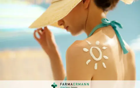 Donna con cappello di paglia e crema solare a forma di sole sulla spalla, per proteggere la pelle dal sole.