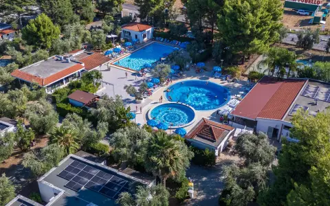 Viste panoramiche del Sea Garden Club Vieste: piscine, ombrelloni blu e vegetazione rigogliosa.
