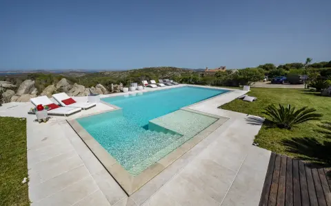 Lussuosa piscina in Sardegna, con vista mare e colline. Ideale per rilassarsi dopo un viaggio in traghetto.