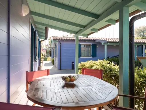 Tavolo con frutta su un portico colorato, con casette in stile villaggi Conero sul mare per bambini sullo sfondo.