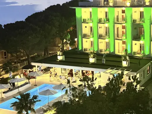 Hotel Biondi Cesenatico: piscina illuminata e facciata verde brillante. Le recensioni lodano l'atmosfera serale.