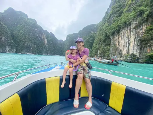 Mom and daughter in Thailand con bambini, navigano su un motoscafo tra scogliere verdi e acque turchesi.