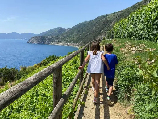 Due bambini esplorano un sentiero panoramico con vista sul mare, un'avventura indimenticabile tra le Cinque Terre con bambini.