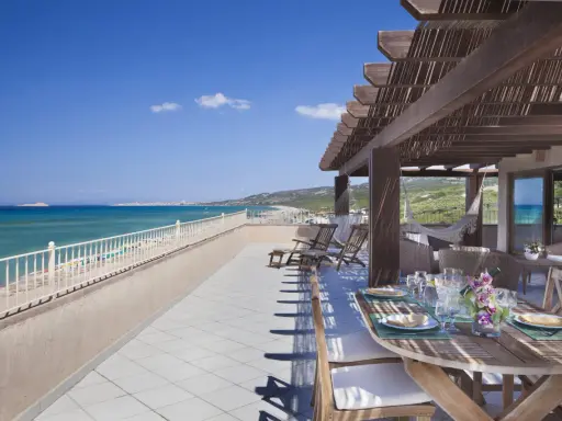 Terrazza con vista mare e tavolo apparecchiato, lettini e amaca. Un sogno al le dune resort.