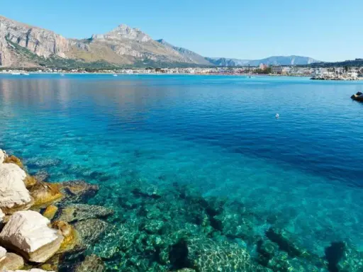 Acque cristalline a San Vito Lo Capo, perfette per una vacanza con bambini. Montagne sullo sfondo, un sogno.