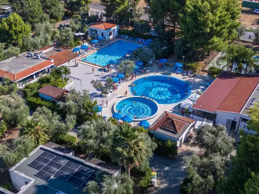 Viste panoramiche del Sea Garden Club Vieste: piscine, ombrelloni blu e vegetazione rigogliosa.