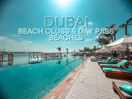 Piscina a sfioro e lettini prendisole in un lussuoso beach club di Dubai, con palme e vista sullo skyline.