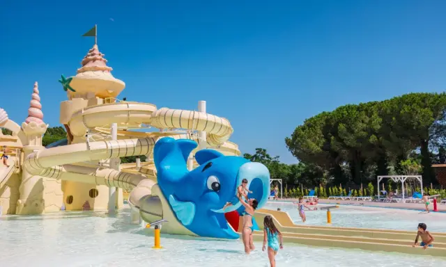 Un parco acquatico con scivoli a forma di castello e balena blu, ideale per campeggi in Toscana sul mare per bambini.