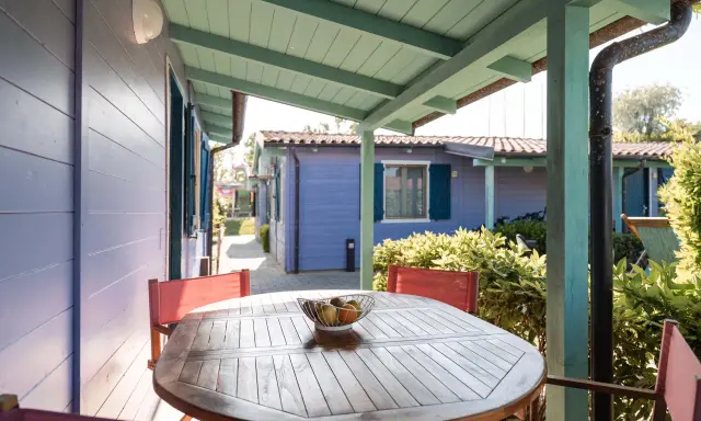 Tavolo con frutta su un portico colorato, con casette in stile villaggi Conero sul mare per bambini sullo sfondo.