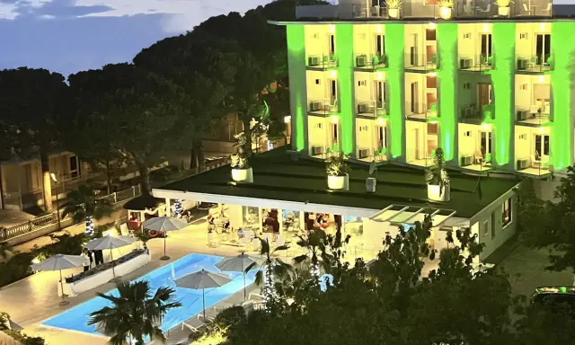 Hotel Biondi Cesenatico: piscina illuminata e facciata verde brillante. Le recensioni lodano l'atmosfera serale.