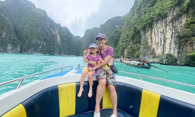 Mom and daughter in Thailand con bambini, navigano su un motoscafo tra scogliere verdi e acque turchesi.