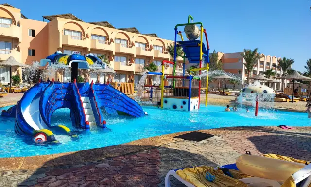 Divertimento acquatico a Marsa Alam con bambini: scivoli blu, giochi d'acqua e piscine cristalline in un resort soleggiato.