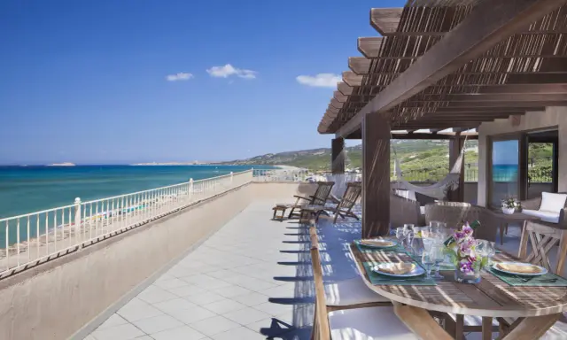 Terrazza con vista mare e tavolo apparecchiato, lettini e amaca. Un sogno al le dune resort.