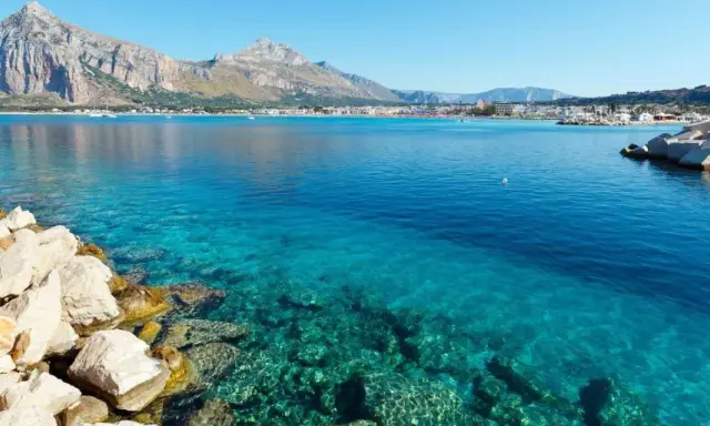 Acque cristalline a San Vito Lo Capo, perfette per una vacanza con bambini. Montagne sullo sfondo, un sogno.