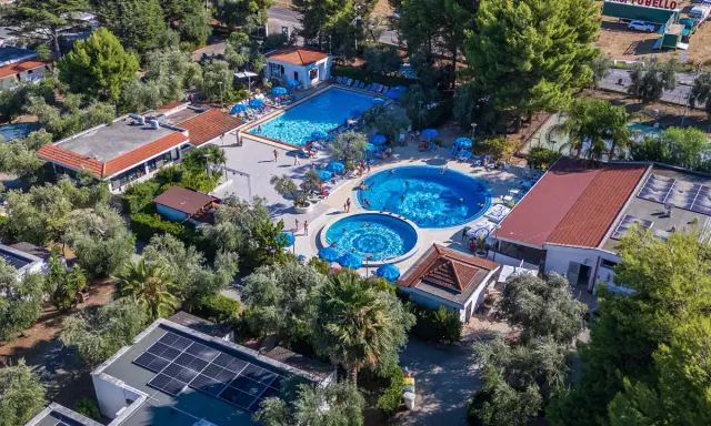 Viste panoramiche del Sea Garden Club Vieste: piscine, ombrelloni blu e vegetazione rigogliosa.
