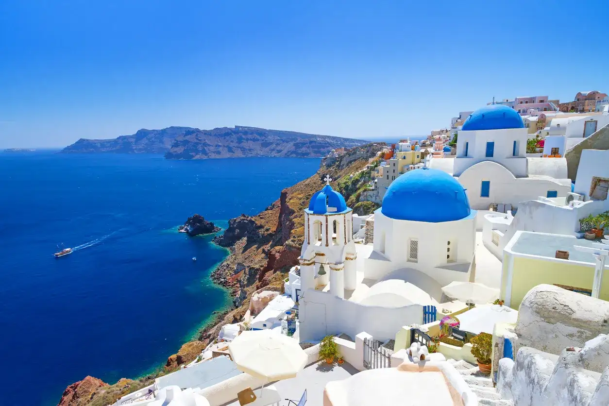 Santorini spiagge: case bianche con cupole blu a picco sul mare blu intenso, un'isola da sogno.