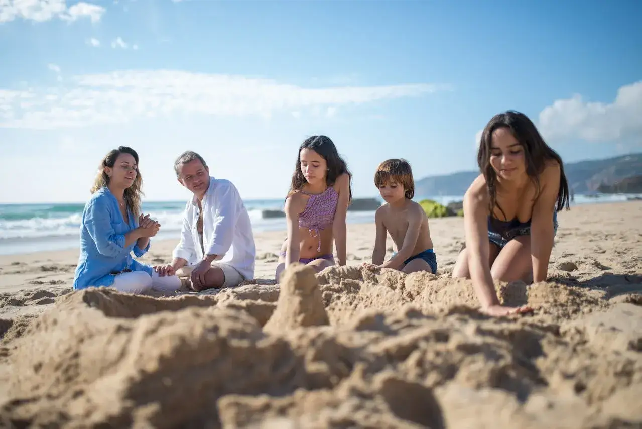 Famiglia felice in vacanza in Thailandia con bambini, costruiscono castelli di sabbia sulla spiaggia.