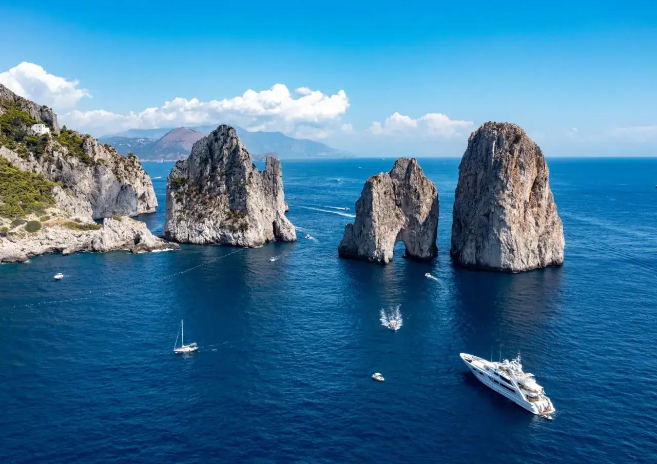 Faraglioni di Capri, un sogno di mare in Campania. Yacht di lusso e barche navigano nelle acque cristalline.