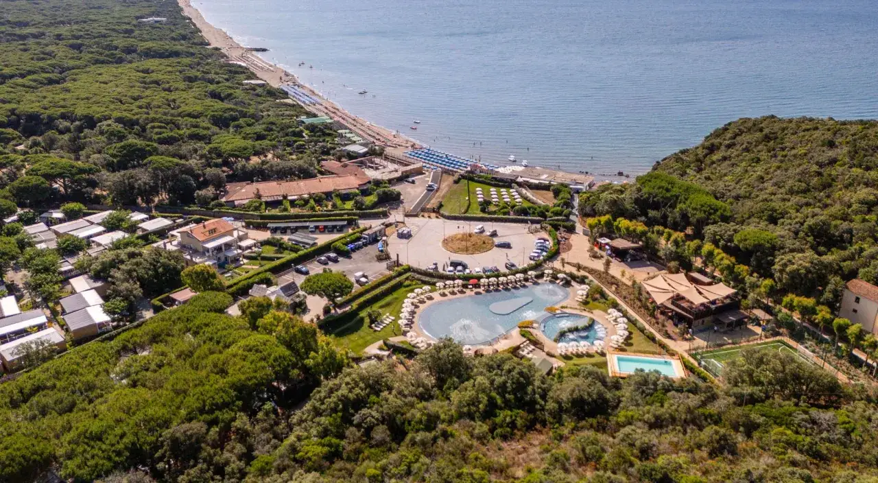 Villaggio toscana sul mare con spiaggia, piscina, campi sportivi e bungalow immersi nel verde.