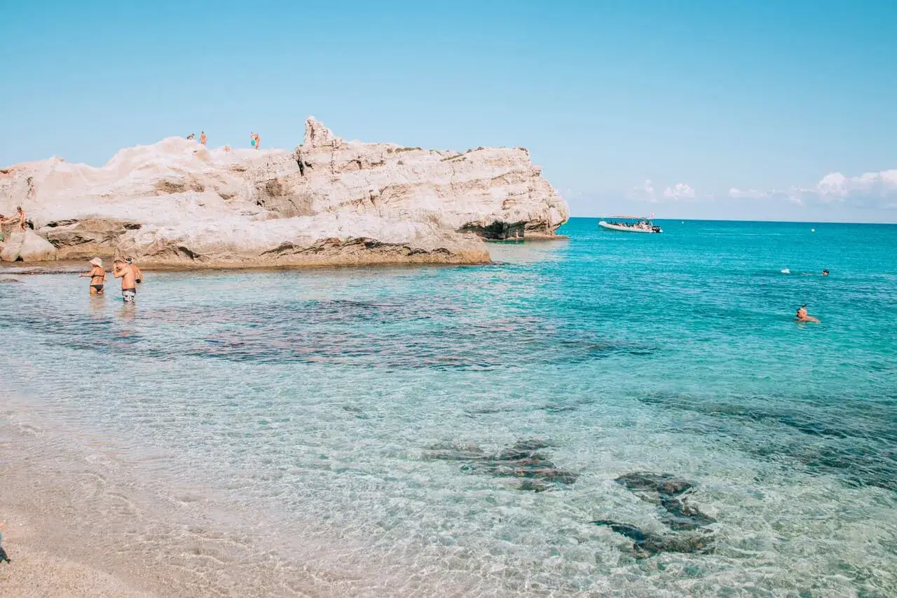 Spiaggia con scogli bianchi e mare cristallino, ideale tra i posti da visitare in Calabria con bambini per un bagno rinfrescante.