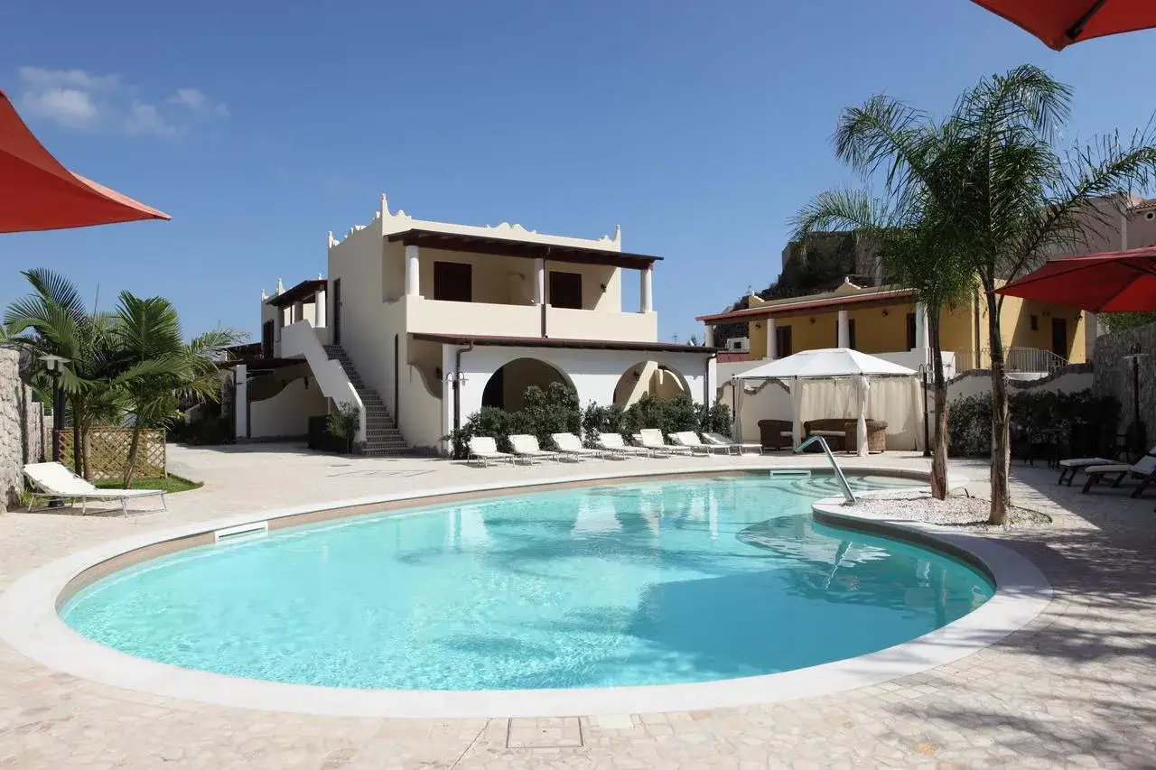 Piscina eoliana con lettini e palme, ideale per vacanze con bambini.