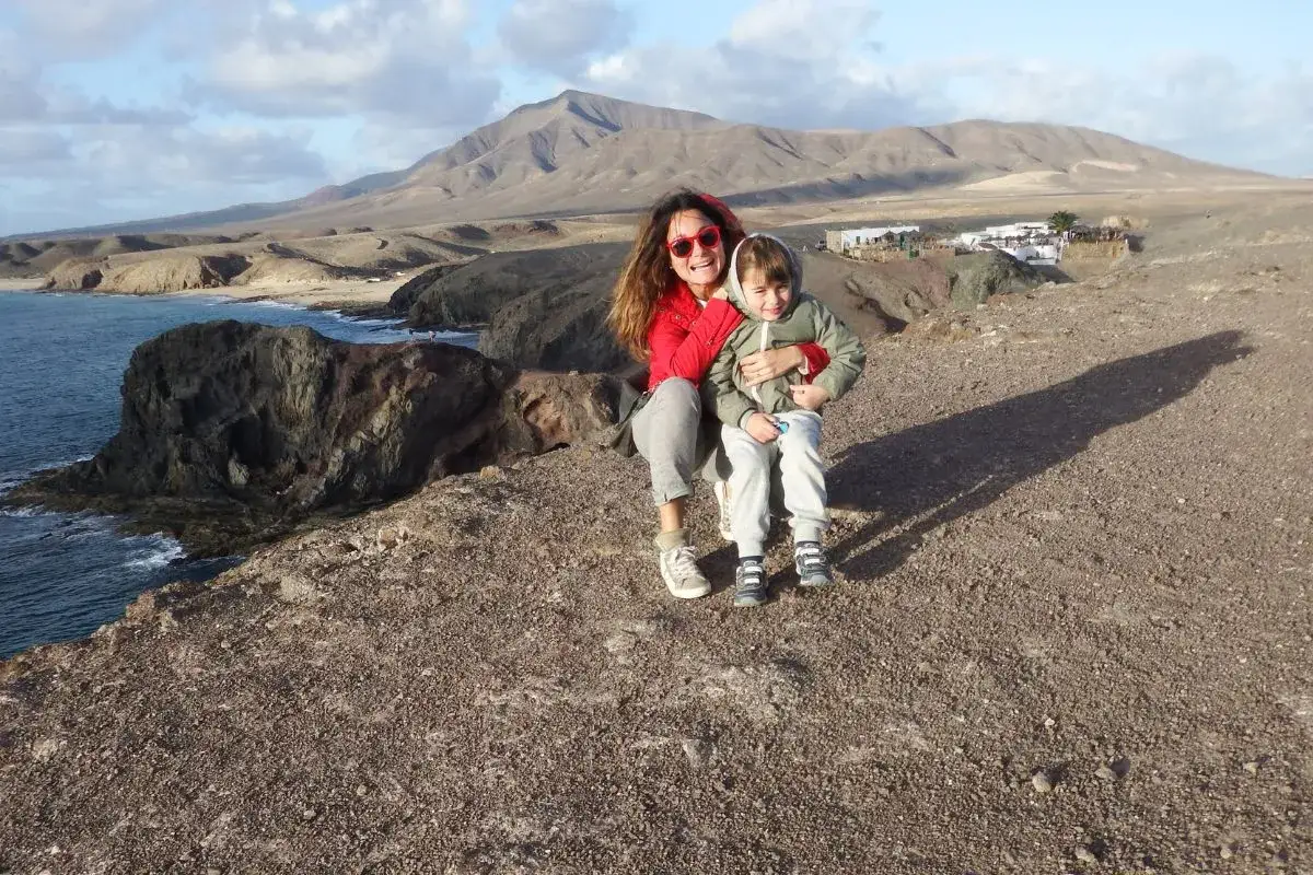 Mom and child enjoy a scenic view on Lanzarote con bambini. Mountains and ocean in the background.