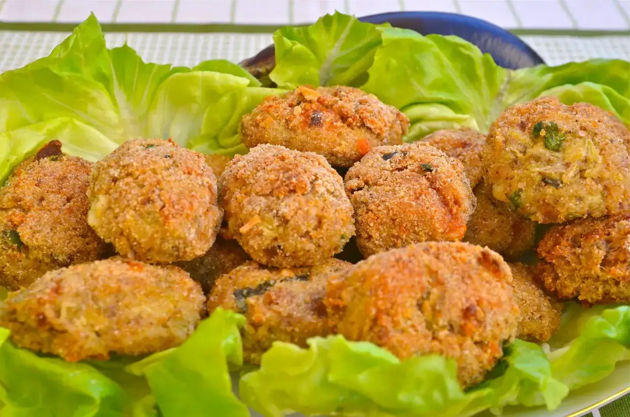 Polpette di melanzane dorate e croccanti, servite su un letto di lattuga fresca. Un antipasto gustoso e leggero.