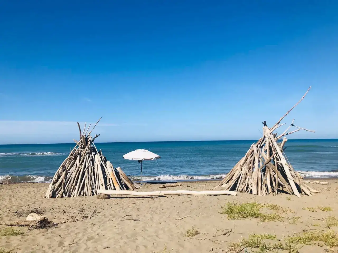 Capanna di legni sulla spiaggia della Maremma, perfetta per giocare con i bambini. Mare azzurro e cielo limpido.