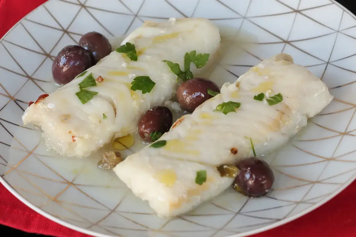 Due filetti di merluzzo cotti in padella con olive nere e prezzemolo. Chissà quanto pesa un merluzzo così delizioso!