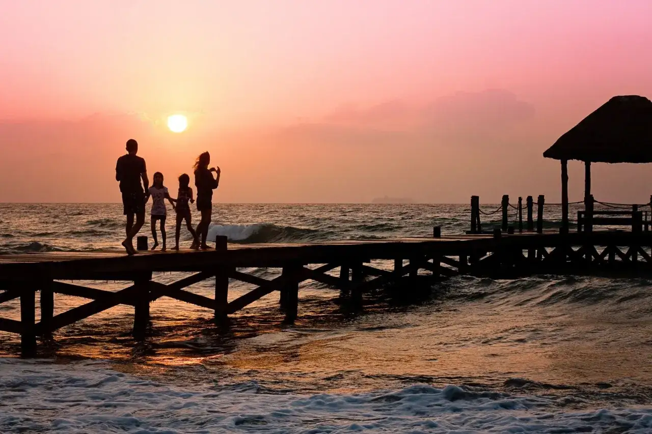 Famiglia in vacanza sulla costa azzurra al tramonto, camminano su un pontile con bambini.