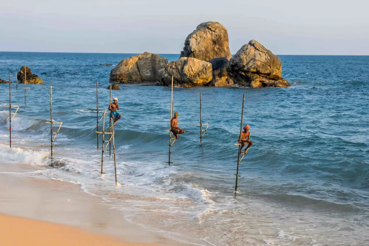 Pescatori su palafitte in Sri Lanka, un'immagine iconica che ricorda la vita e le tradizioni locali, come se fossero bambini che giocano in mare.