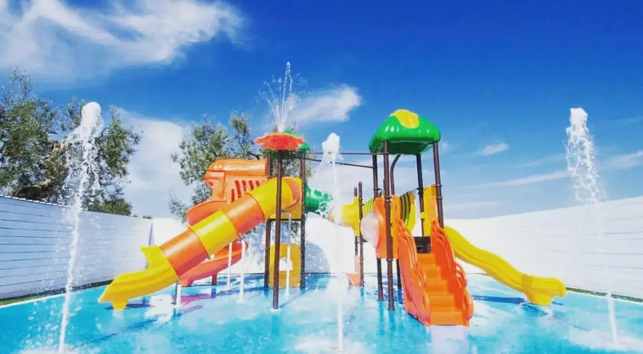 Scivoli acquatici colorati e fontane zampillanti in una piscina, perfetti per le vacanze nelle masserie per bambini in Puglia.