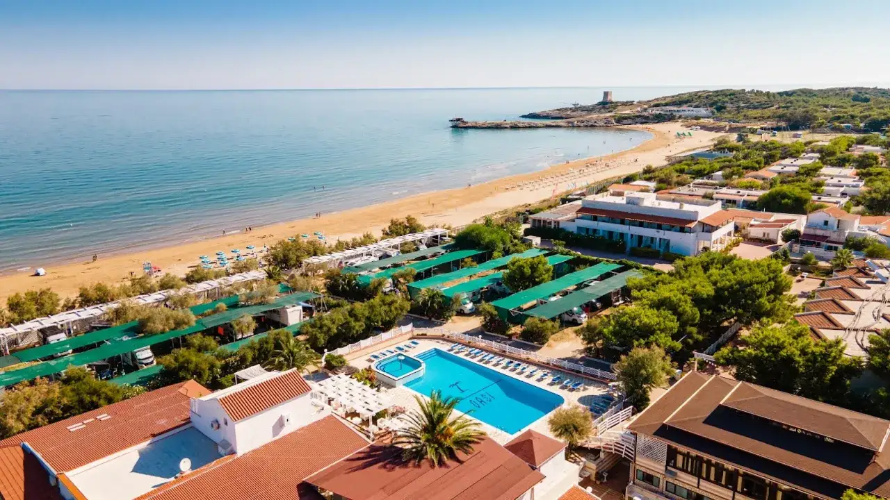 Vista aerea del Sea Garden Club Vieste: spiaggia dorata, mare azzurro, piscina scintillante e bungalow immersi nel verde.