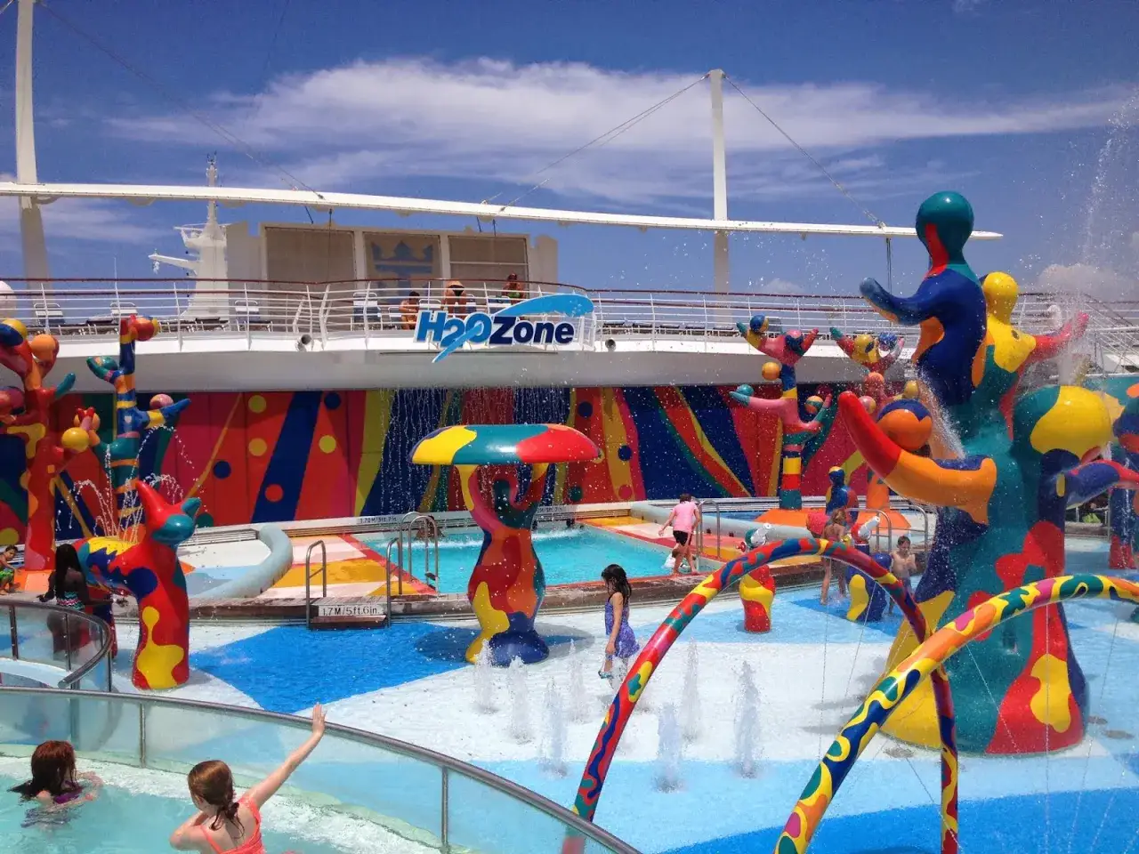 Area acquatica colorata su una nave da crociera, con bambini che giocano tra spruzzi d'acqua e scivoli. Divertimento assicurato per la crociera bambini!