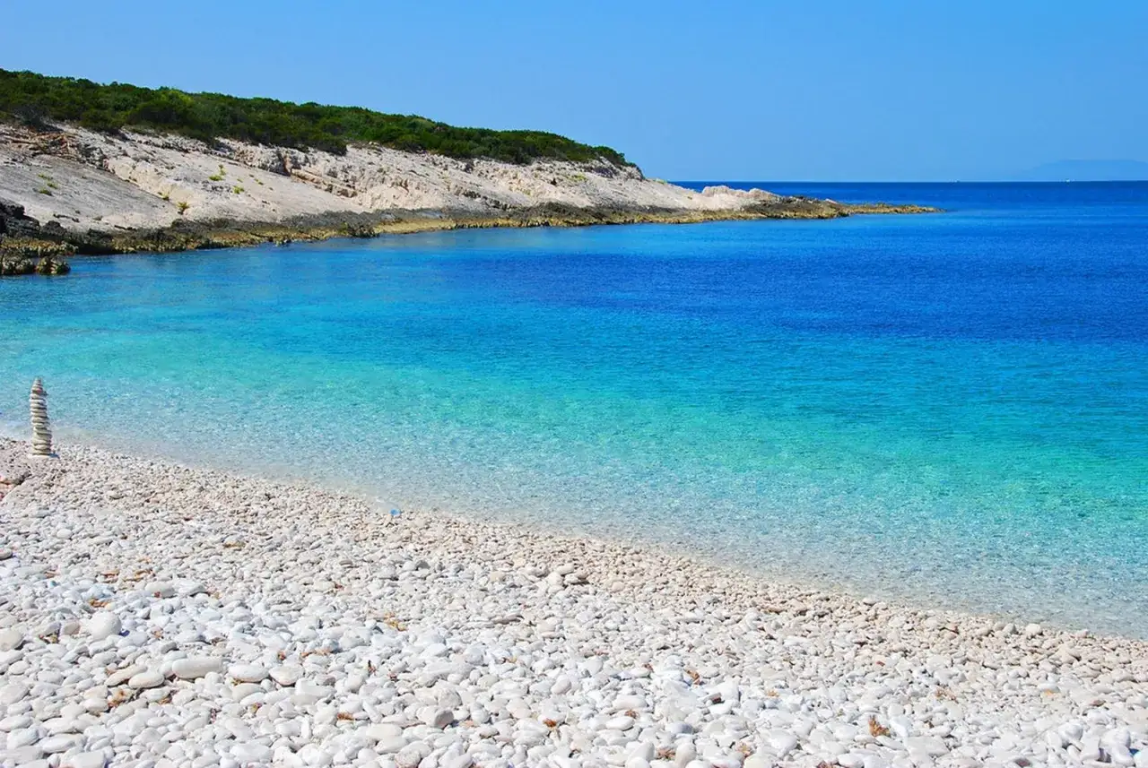 Spiaggia di ciottoli bianchi baciata da un mare cristallino e turchese in Croazia. Un angolo di paradiso per rilassarsi.