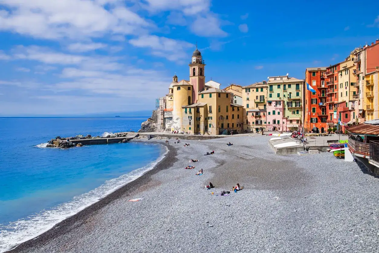 Colorate case liguri si affacciano su una spiaggia di ciottoli e sul blu intenso del mare.