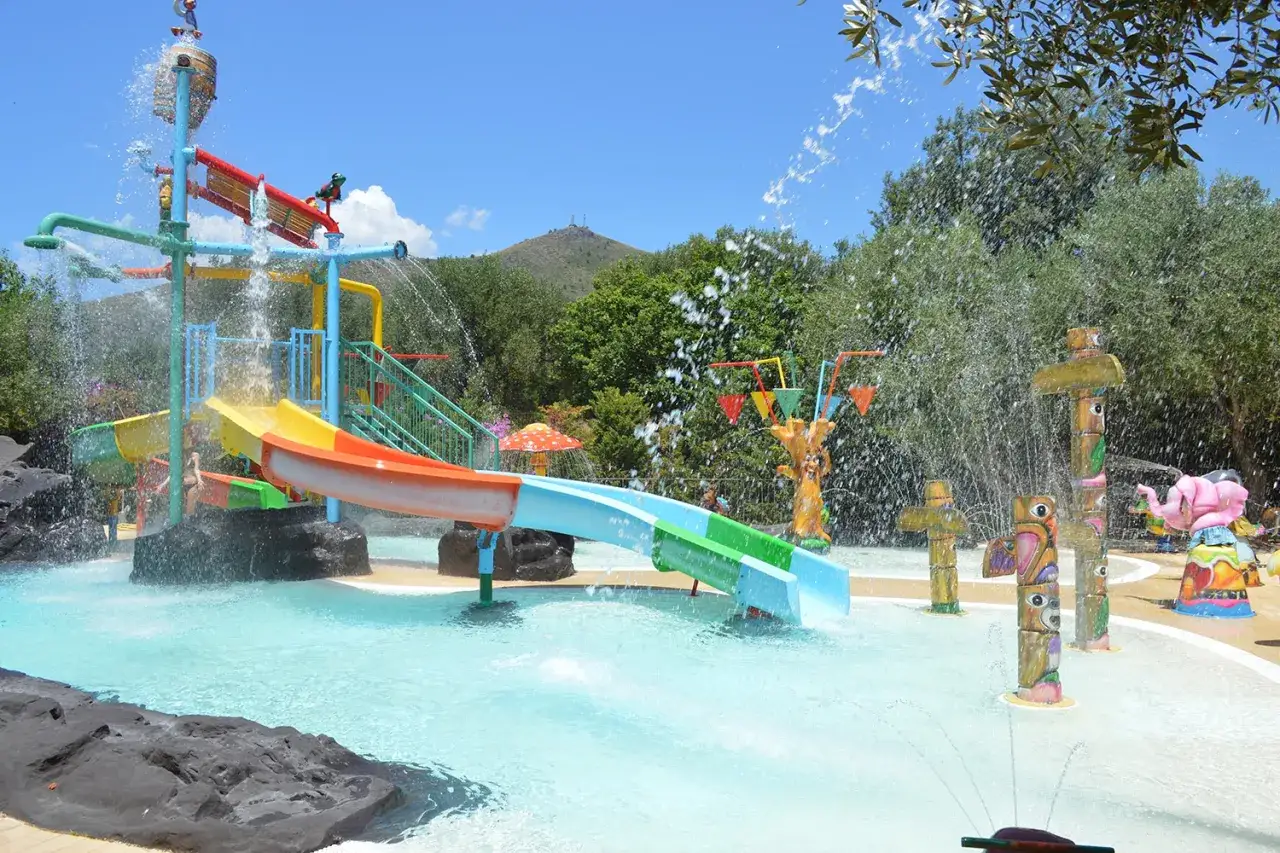 Scivoli colorati e giochi d'acqua in un parco acquatico, ideale per chi cerca i migliori villaggi turistici in Italia sul mare per divertirsi in famiglia.