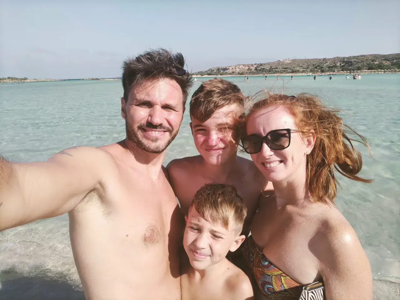 Famiglia felice a Creta, con bambini che giocano nell'acqua cristallina.