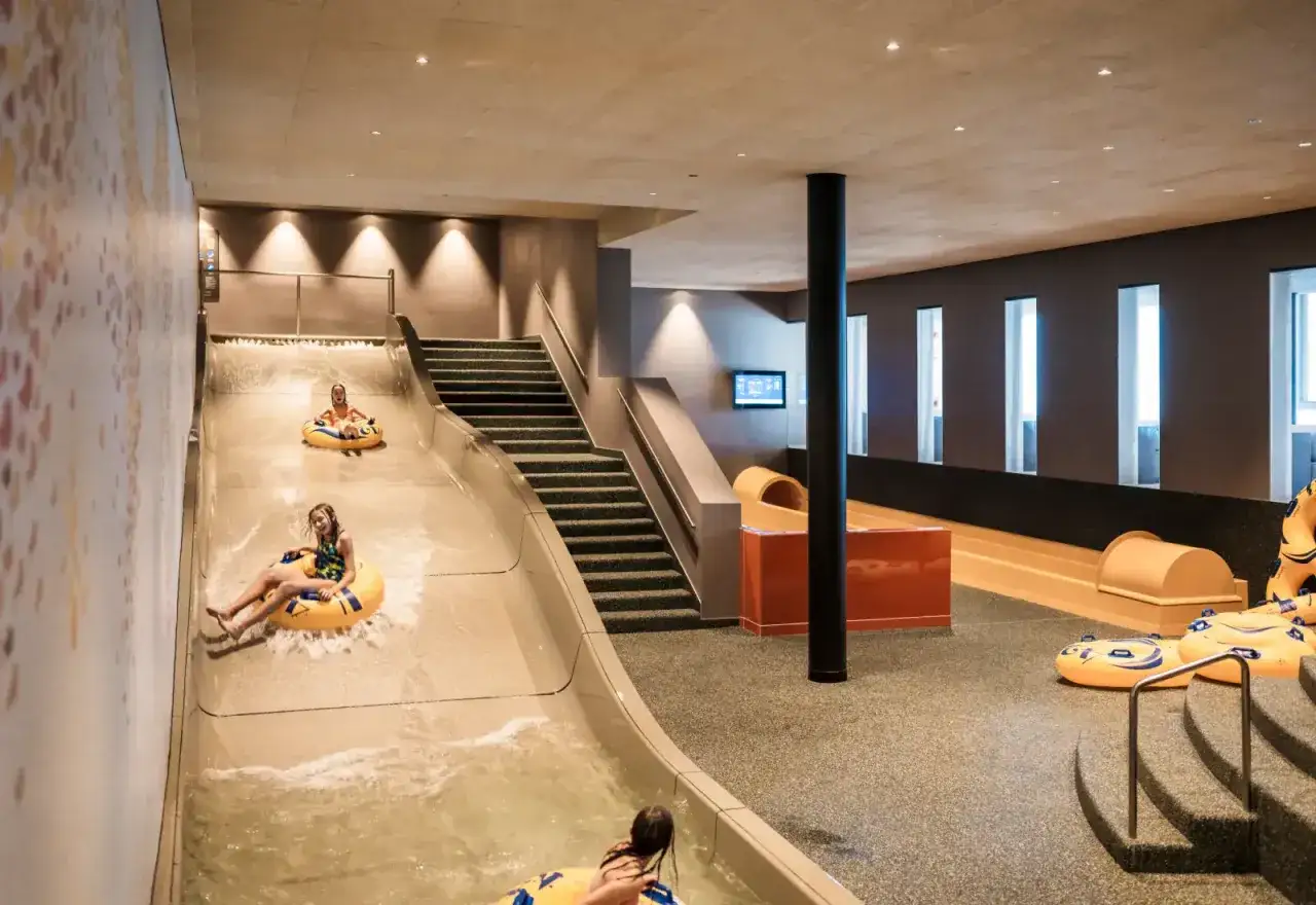 Bambini si divertono sullo scivolo acquatico dell' Aki Family Resort Plose, scendendo con ciambelle gonfiabili.