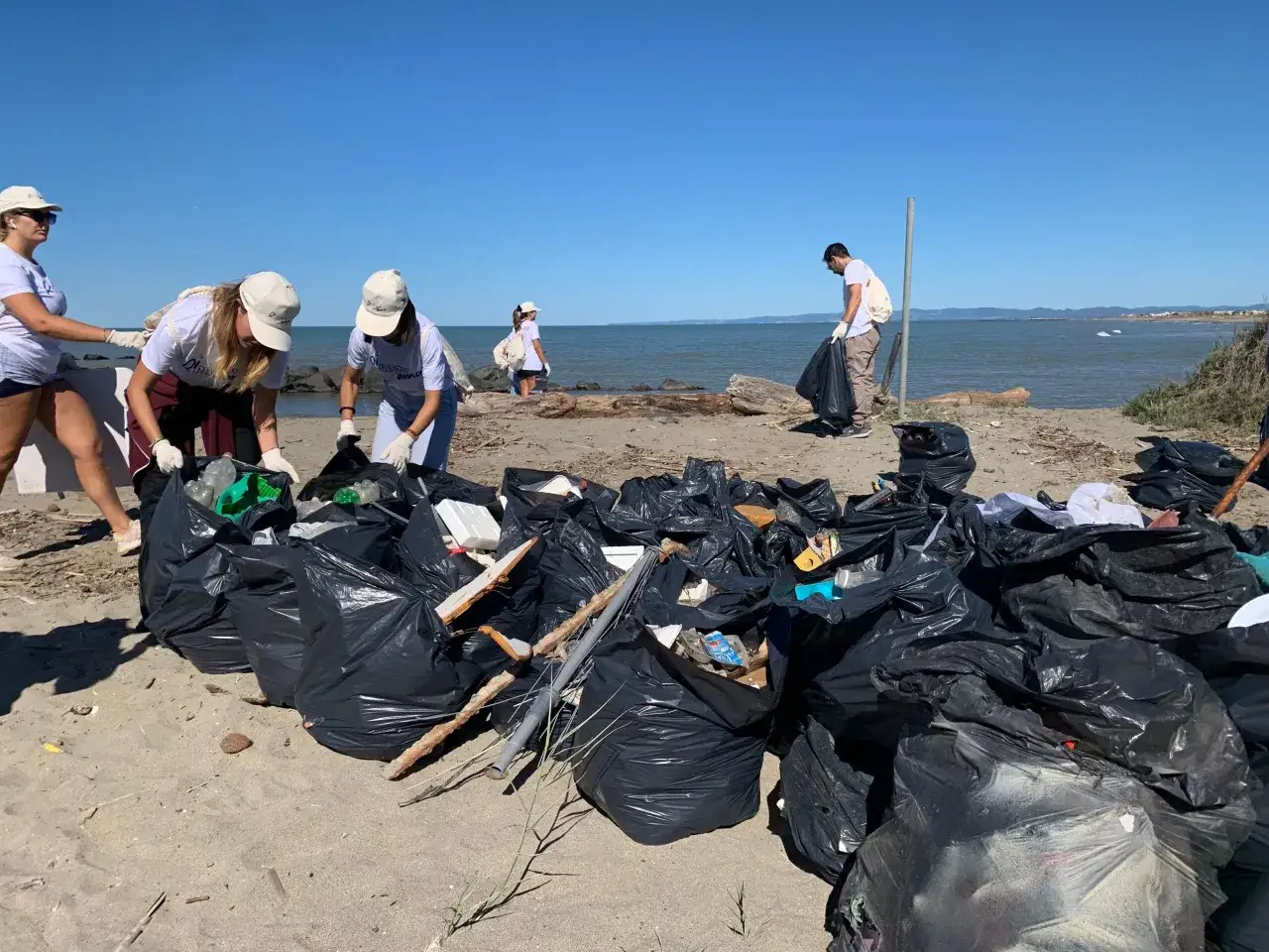 Volontari raccolgono rifiuti sulla spiaggia, un esempio di come agire per 5 modi per salvare il mare.