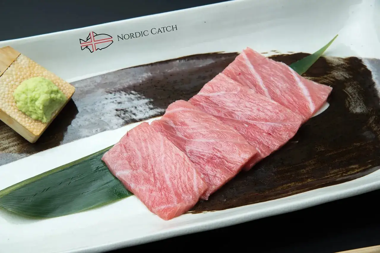Fette di tonno rosso giapponese, fresche e succulente, pronte per essere gustate. Accompagnate da wasabi e una foglia di bambù.